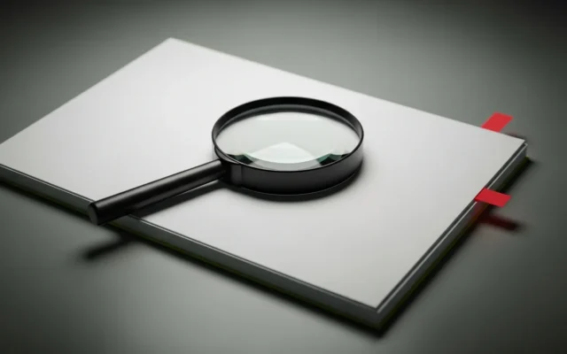 Magnifying glass over a stack of papers with a red flag marker, symbolizing an SEO audit